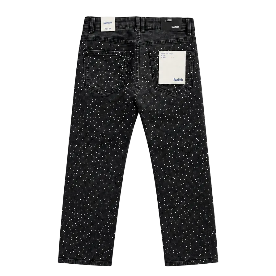 Black denim jeans with a white speckled pattern, shown from the back with a paper tag attached, on a plain white background.